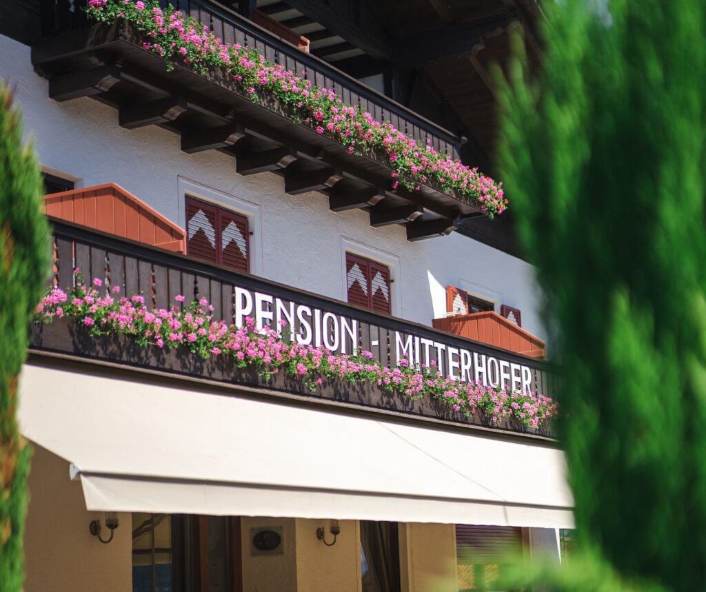 Balconi fioriti con la scritta Pension Mitterhofer sopra la terrazza